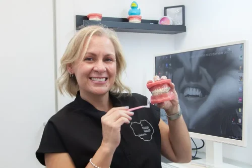 Odontóloga sonriendo con un modelo dental en la Clínica Ricardo Sánchez